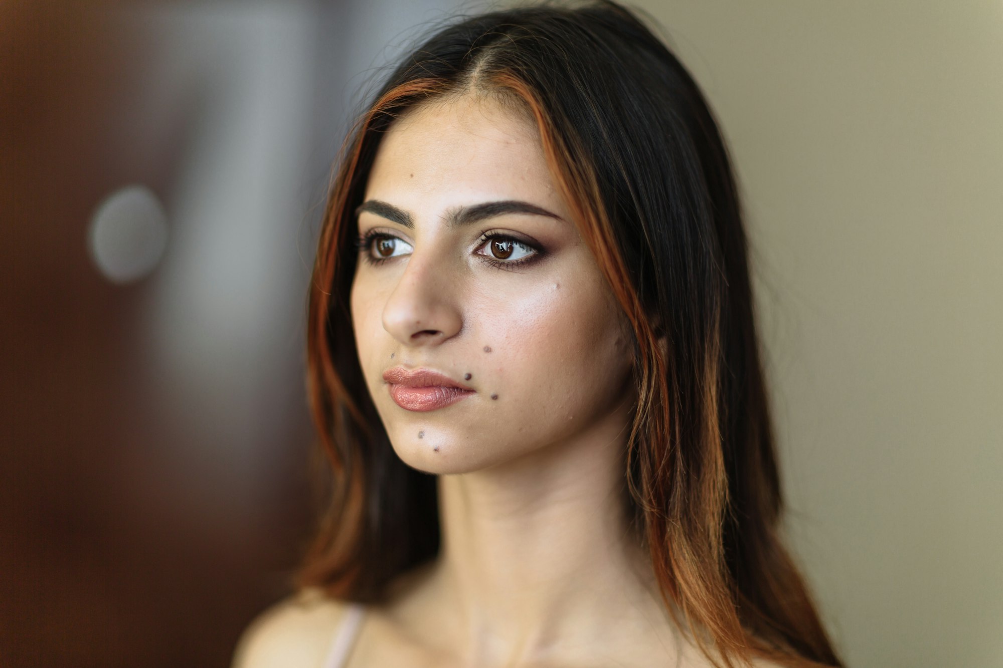 Close-up portrait of young model with moles with makeup in beauty salon