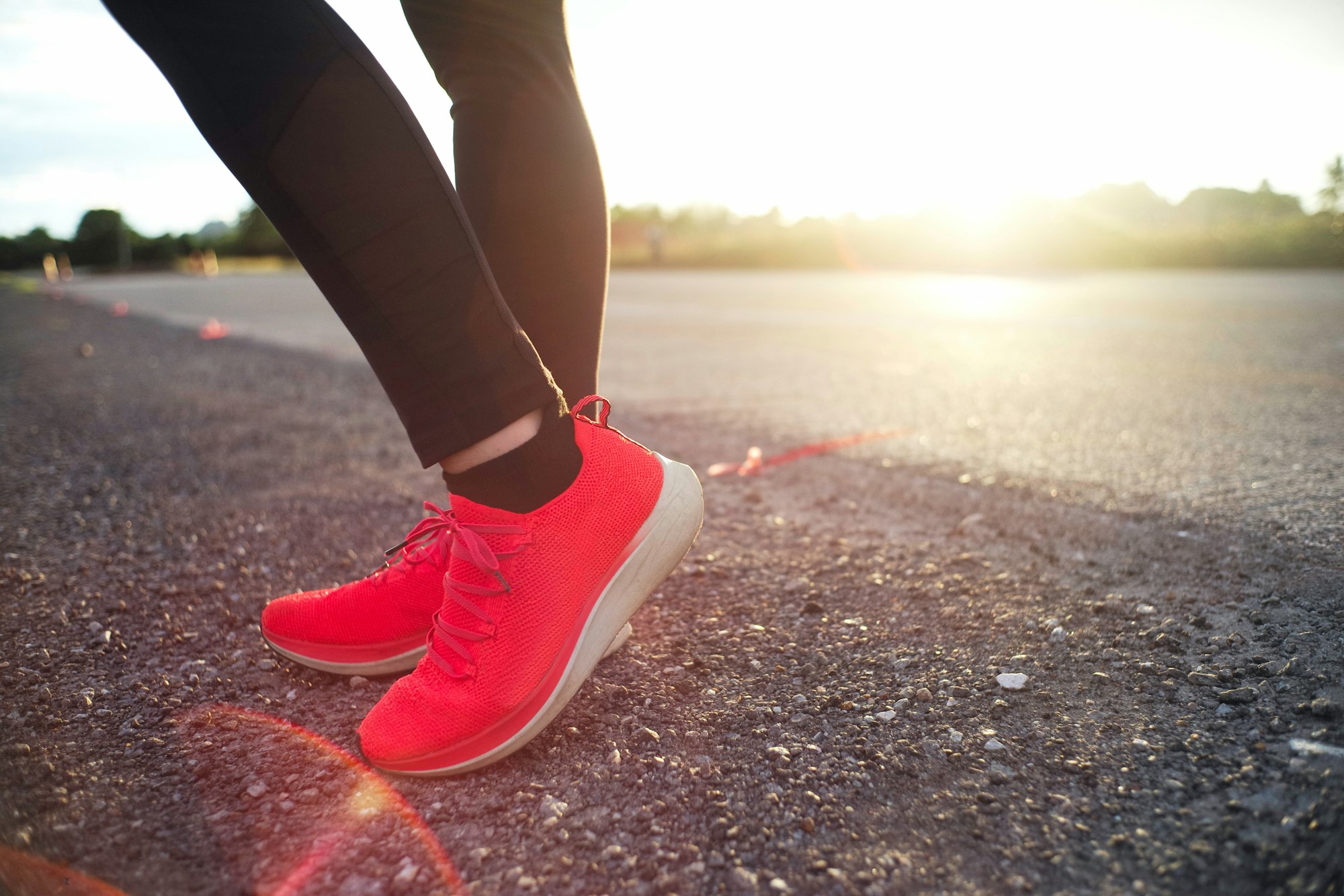 Closeup feet with running shoes standing on the asphalt ground with natural orange light of sunset i