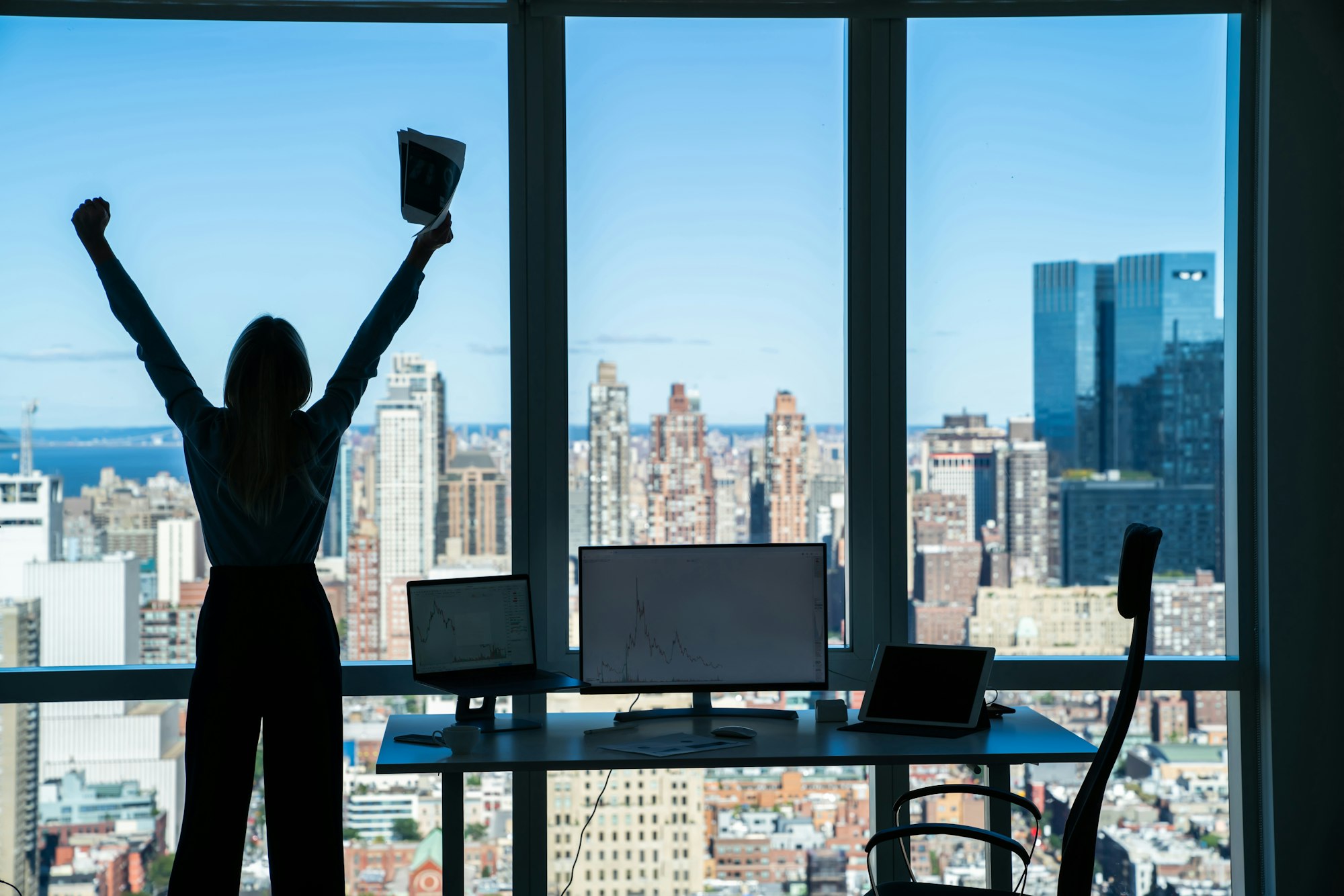 Faceless businesswoman raising arms in satisfaction in contemporary office