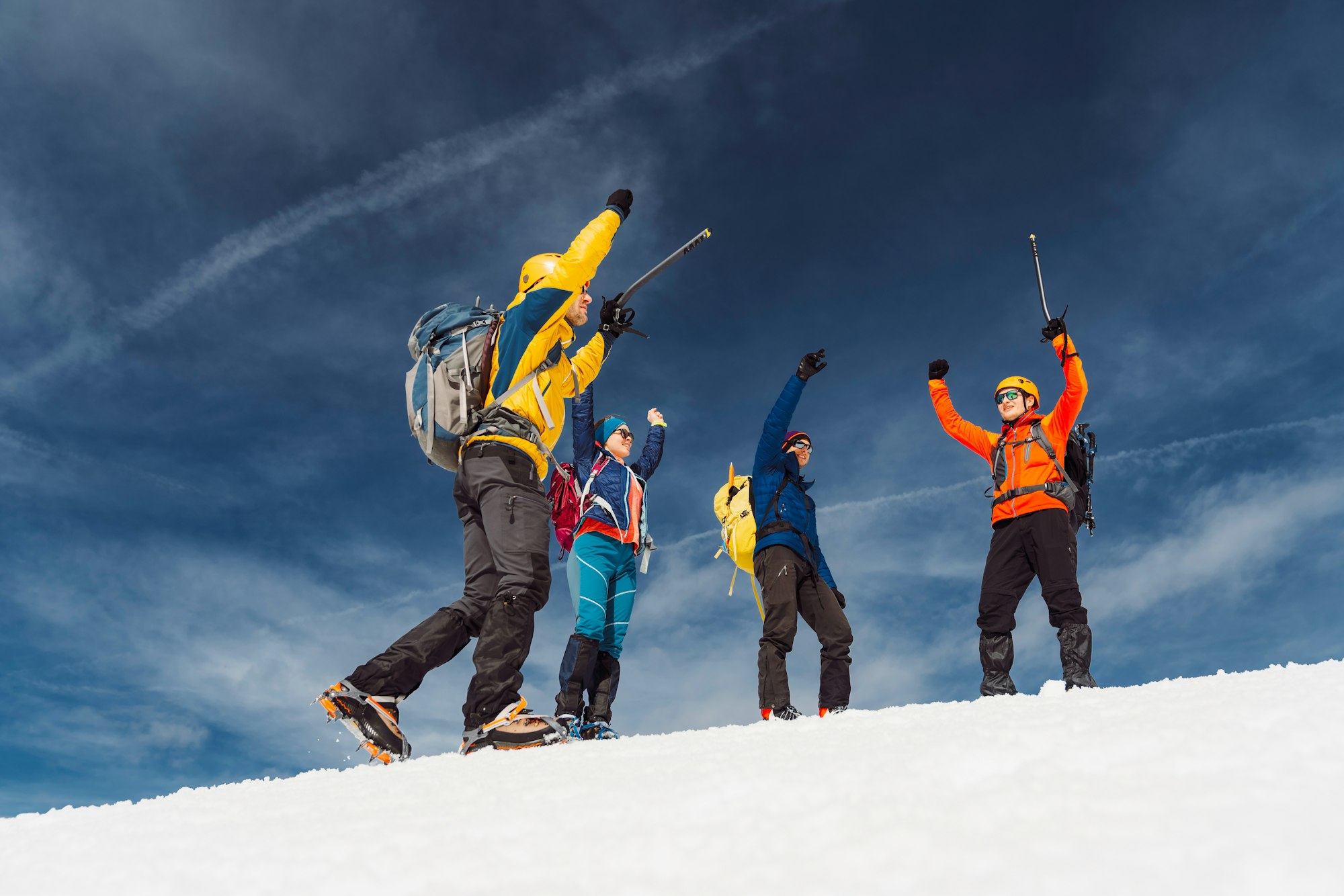 Group of happy hikers with their hands up in the air getting excited to reach the top of the