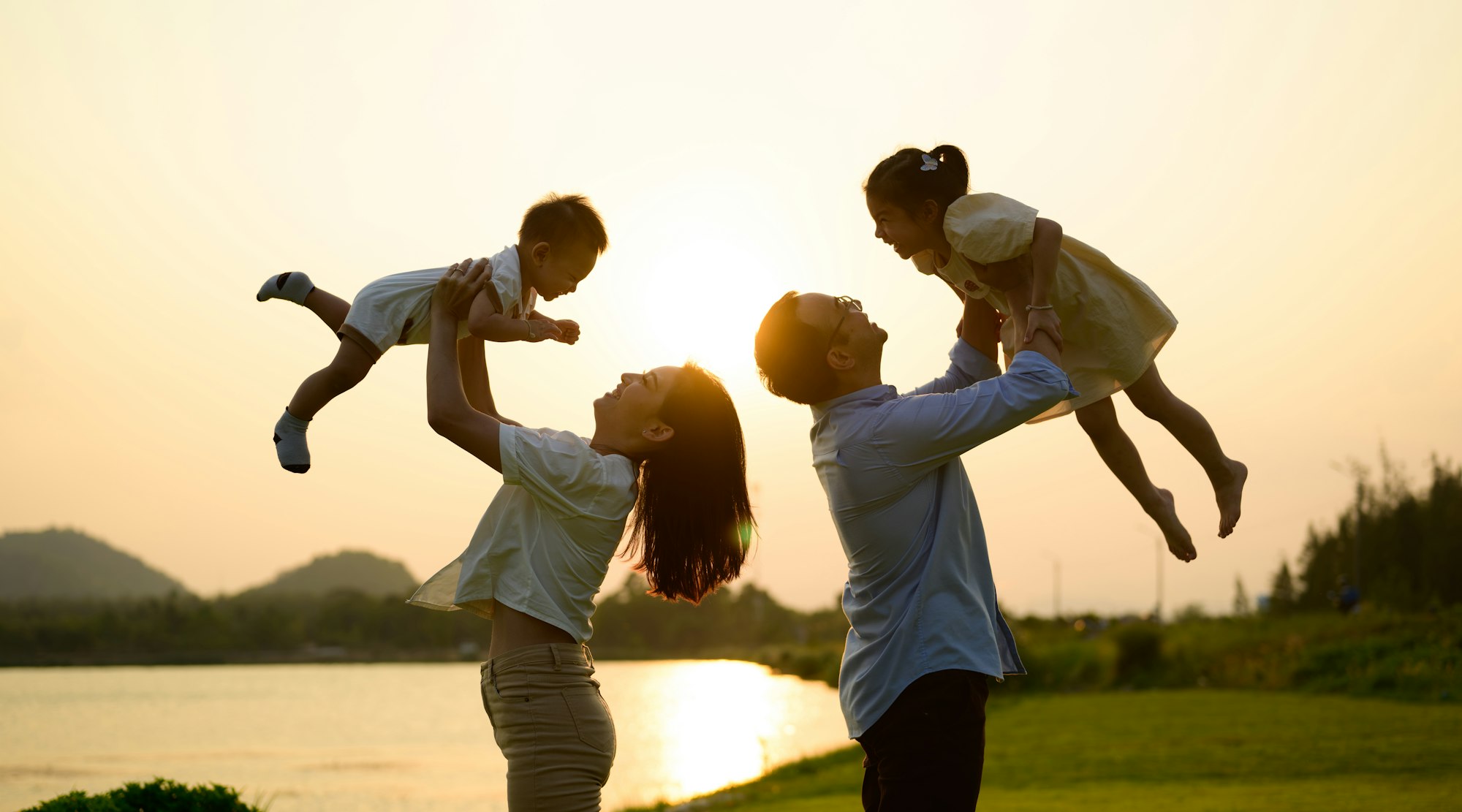 Happy father and mother holding children playing together in park