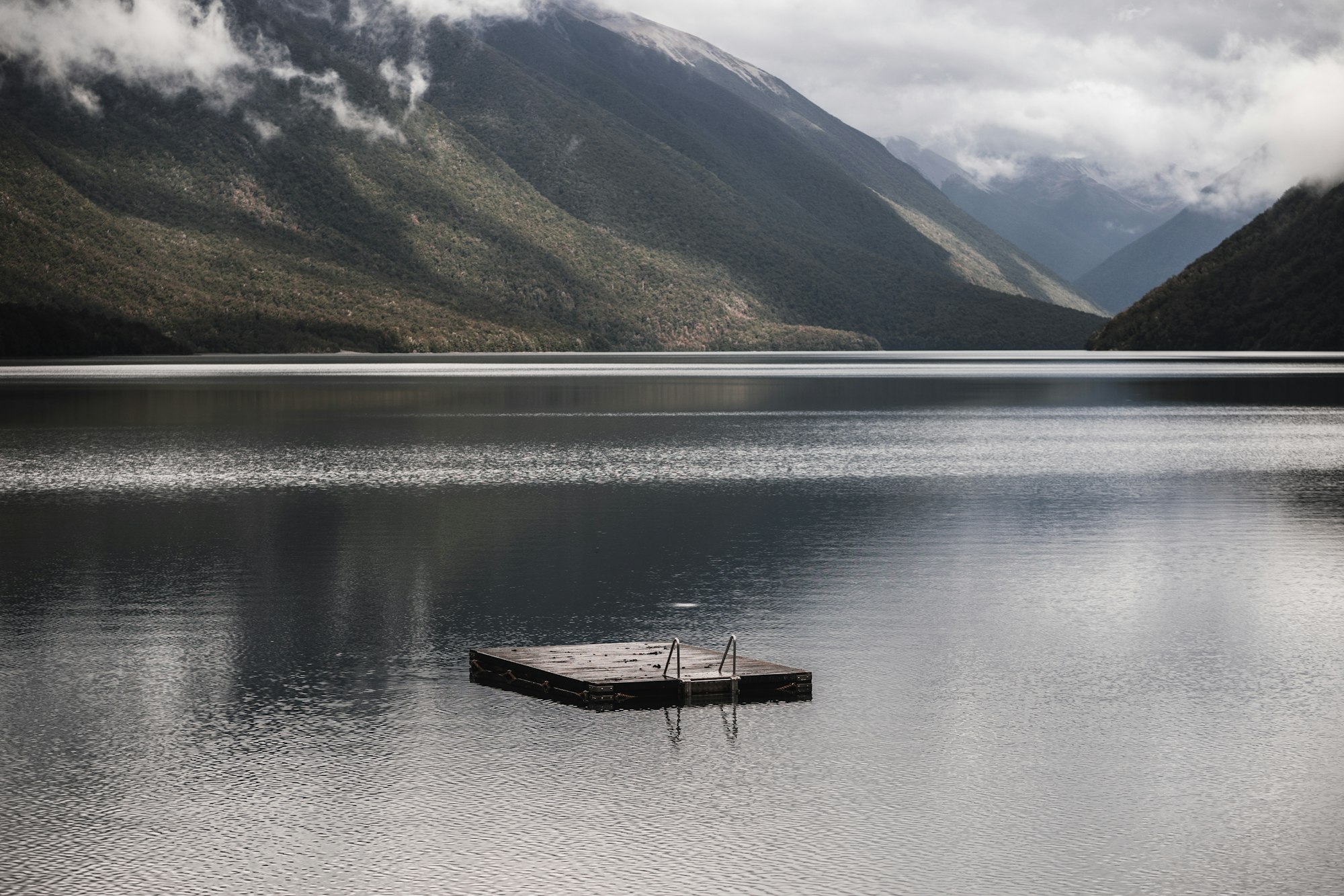 lonely wooden platform with metal ladder to facilitate swimming in the calm lake with rippled water