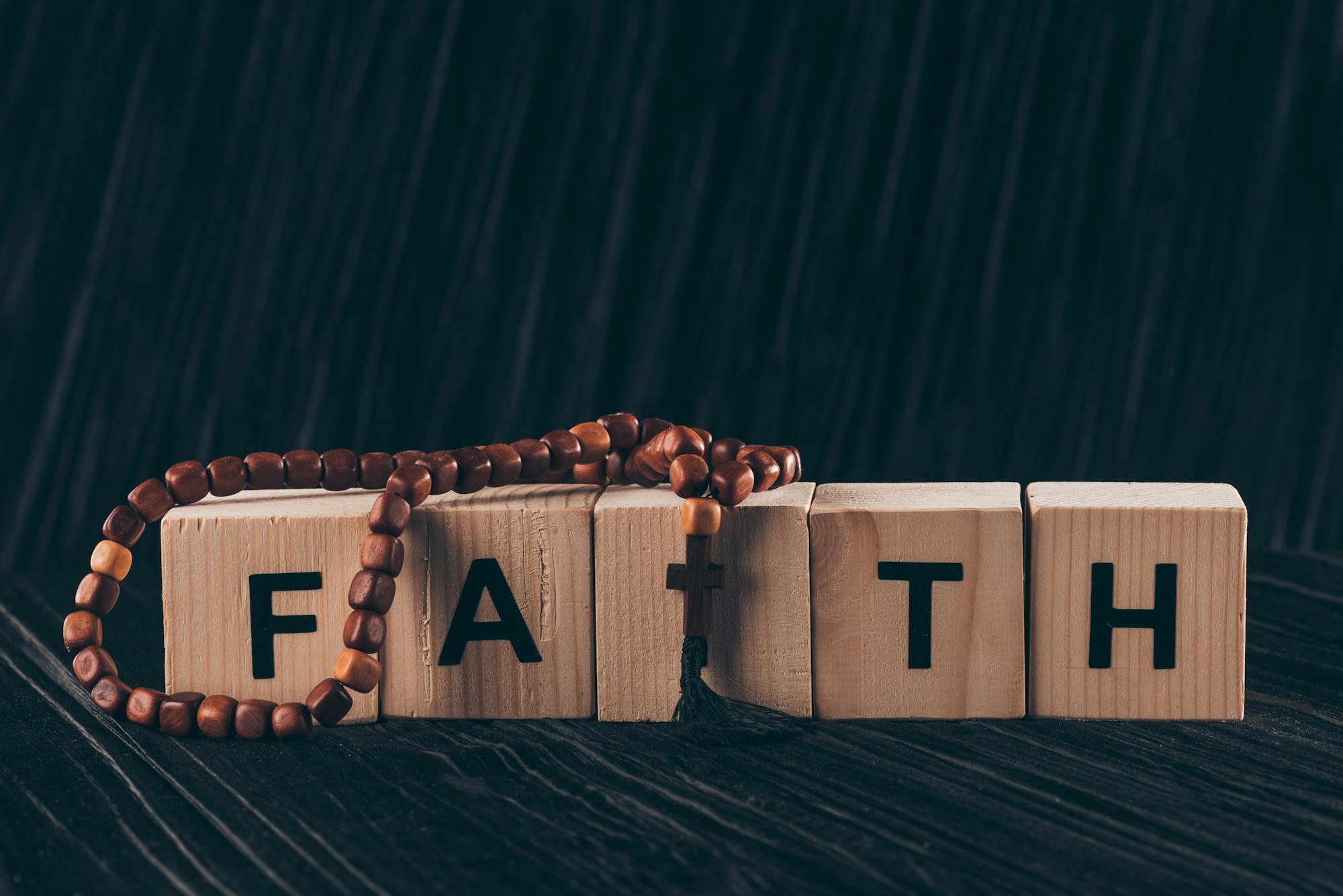 wooden cubes with word Faith and cross on black table