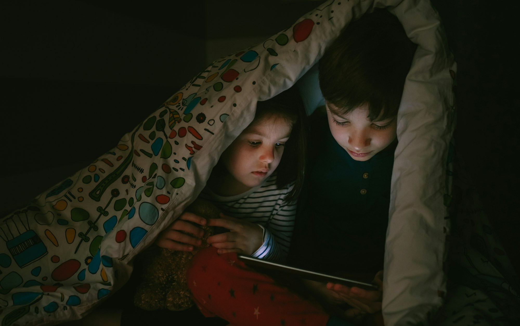 Brothers looking at the tablet in the dark