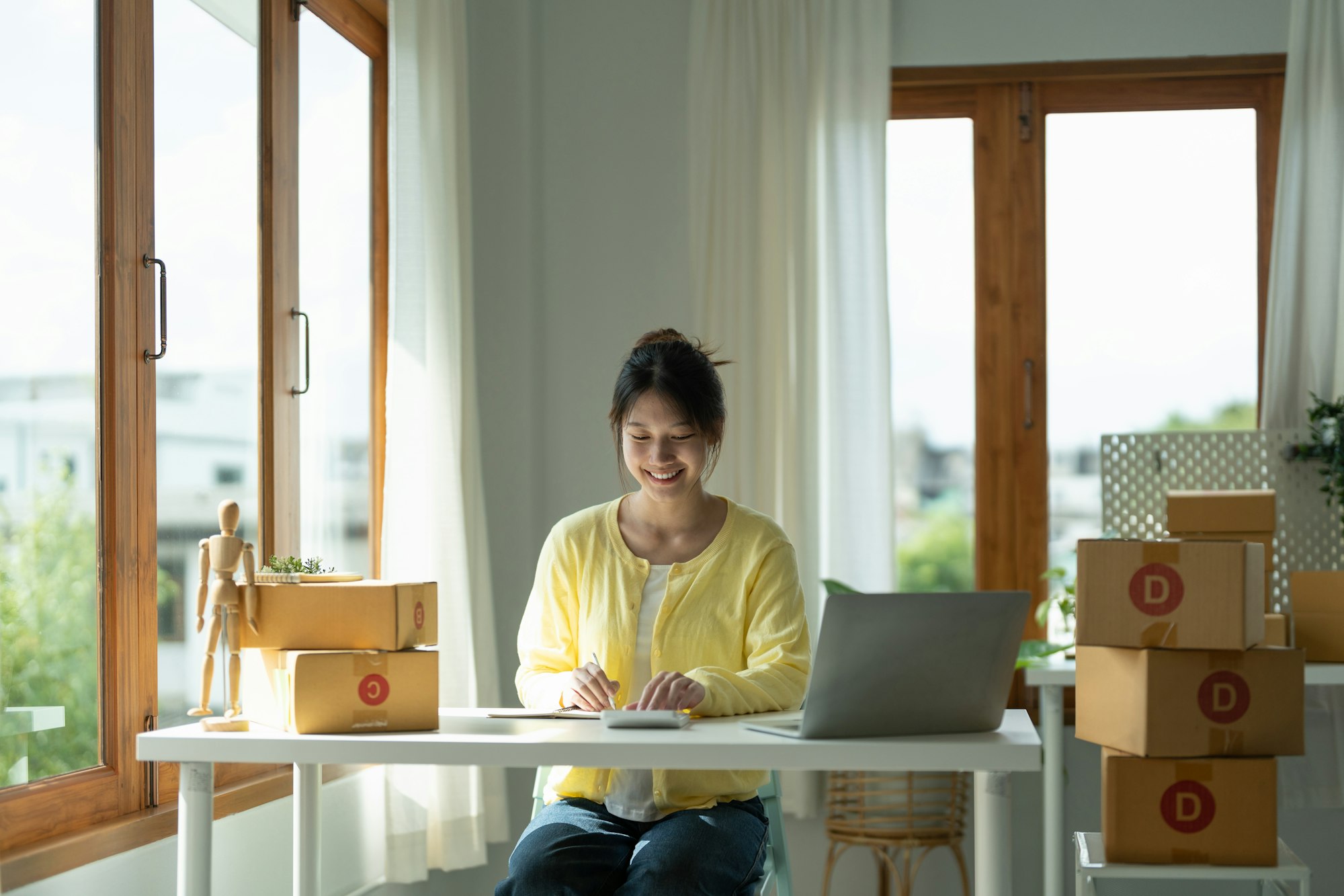 Close up asian female entrepreneur, checks online orders and uses a price calculator to calculate