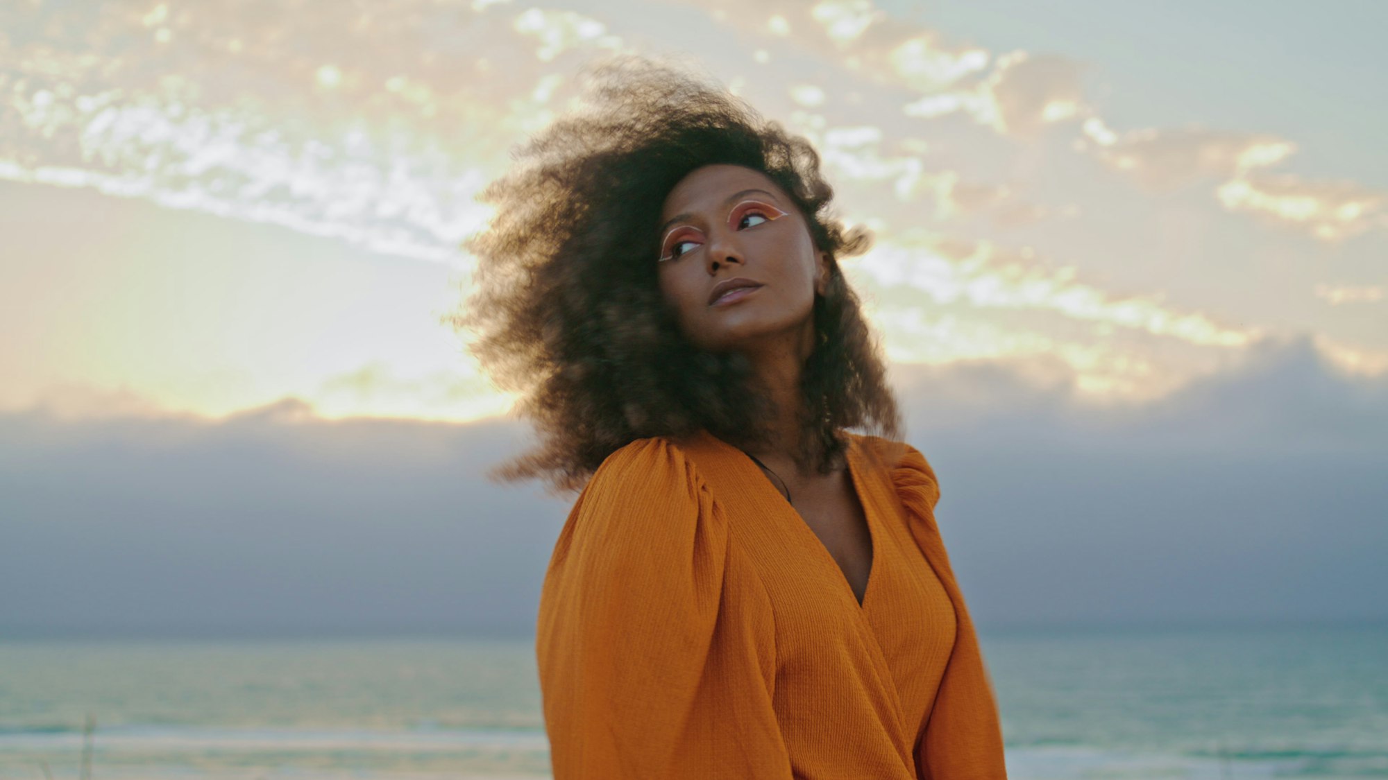 Curly woman posing cloudy summer nature in desert closeup. Portrait pretty model