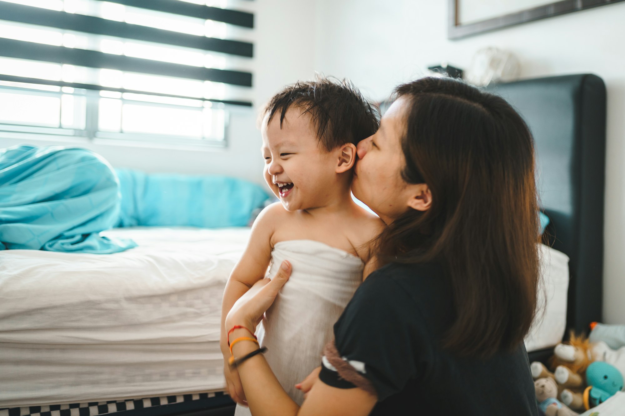 Mother plays with her kid when dressing up after bath.