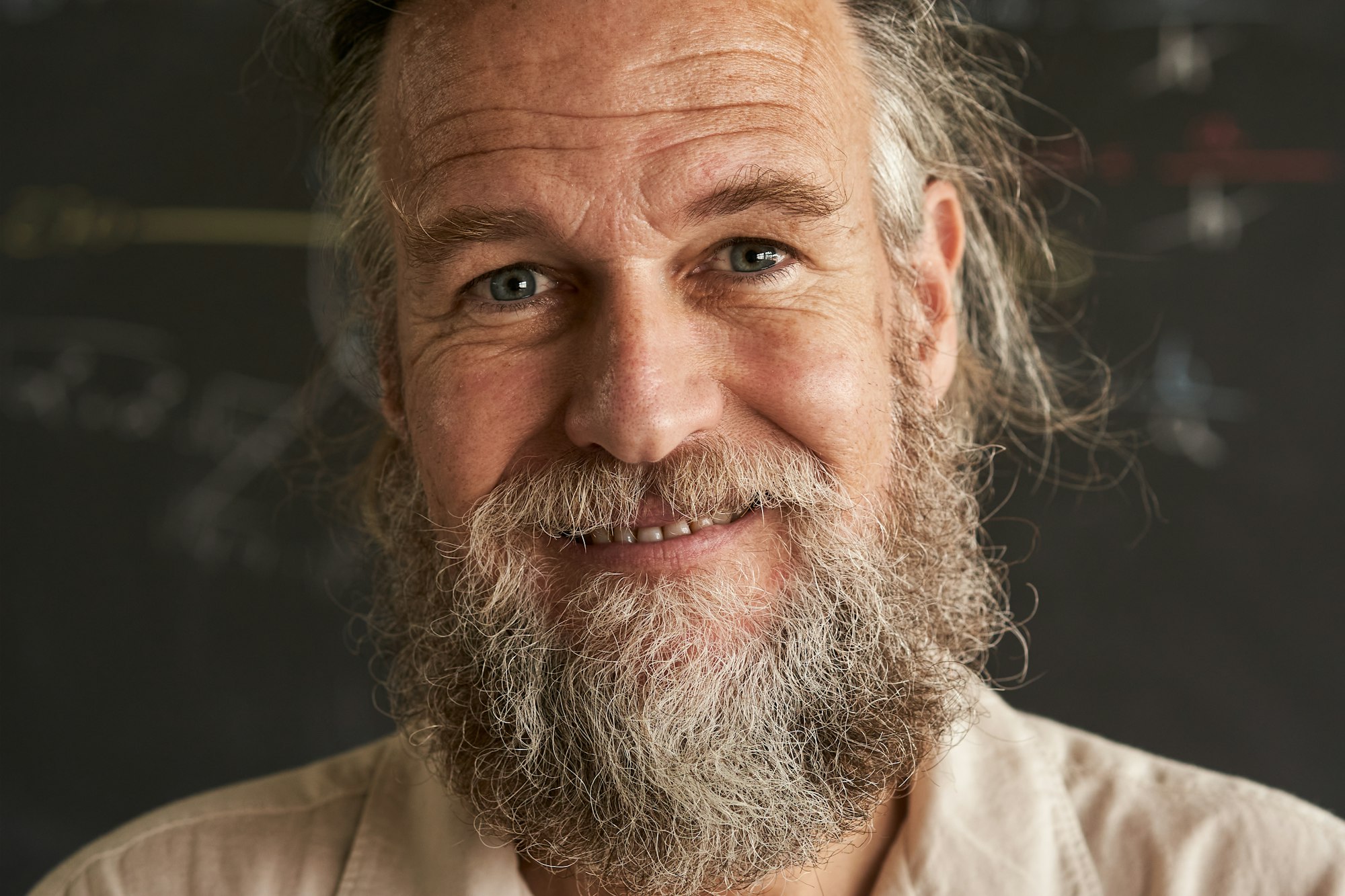 Portrait of an older man with beard and gray hair. The man has a friendly and sincere smile.