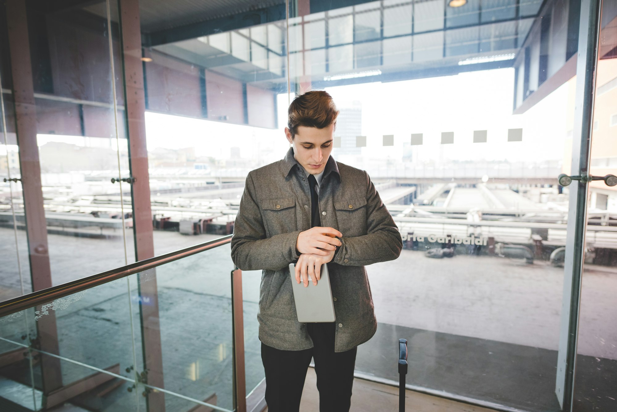 Portrait of young businessman commuter checking wristwatch for time.