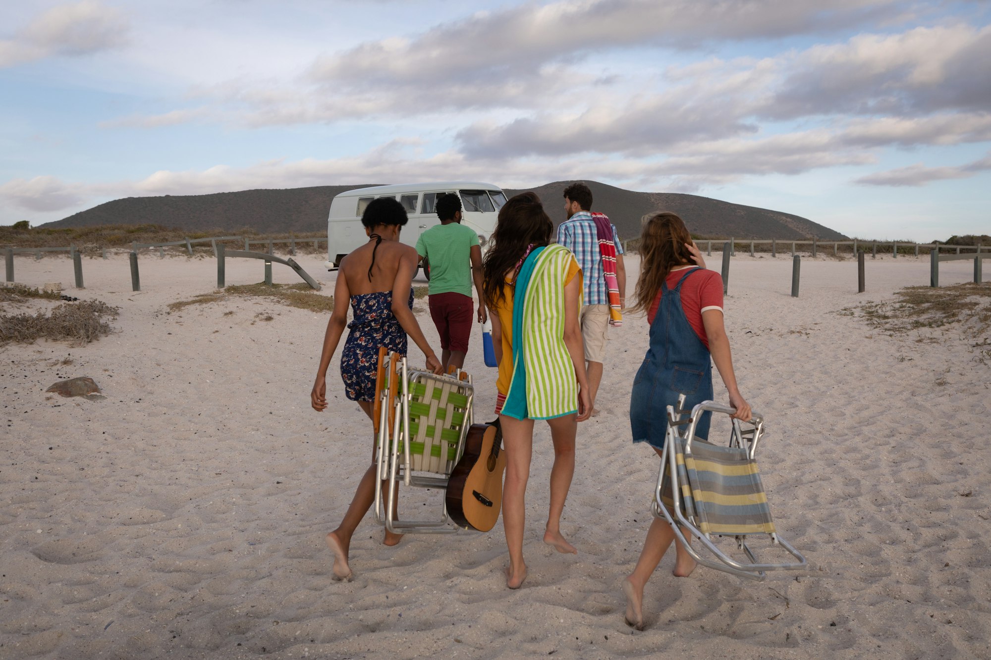 Rear view of multi-ethnic friends come back from beach to join their camper van